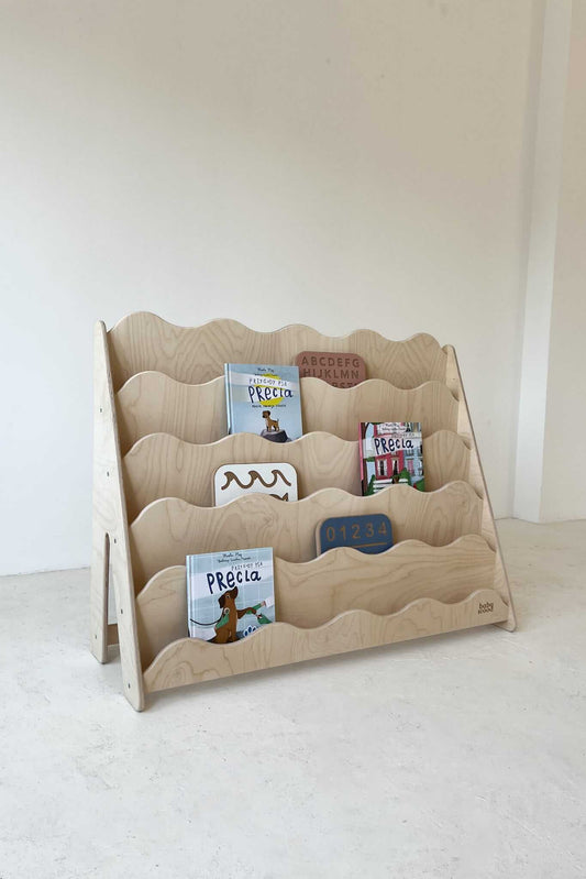 Bücherregal "WAVE" aus Holz, versch. Größen mit bunten Kinderbüchern in sanften Wellenlinien.