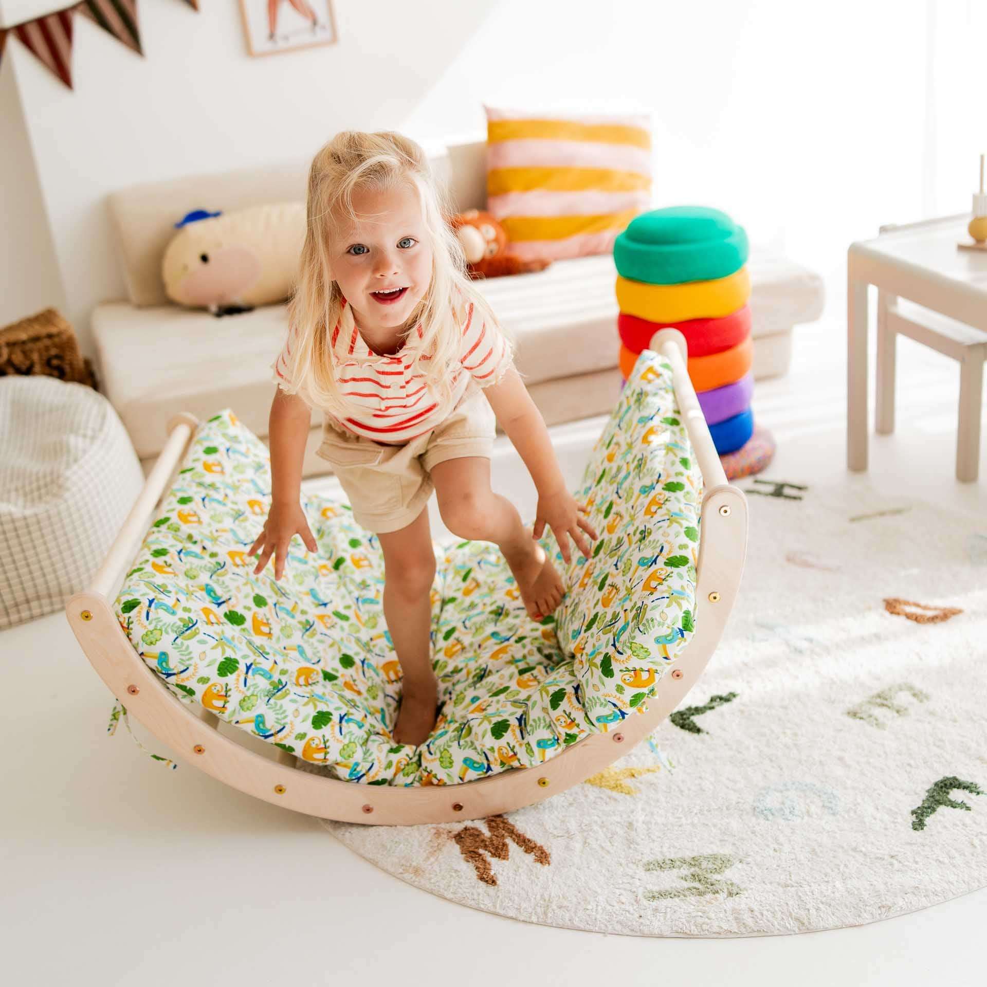 Kind spielt auf dem Kletterbogen Basic aus Holz in buntem Design, fördert Bewegungsfähigkeiten und Spaß.