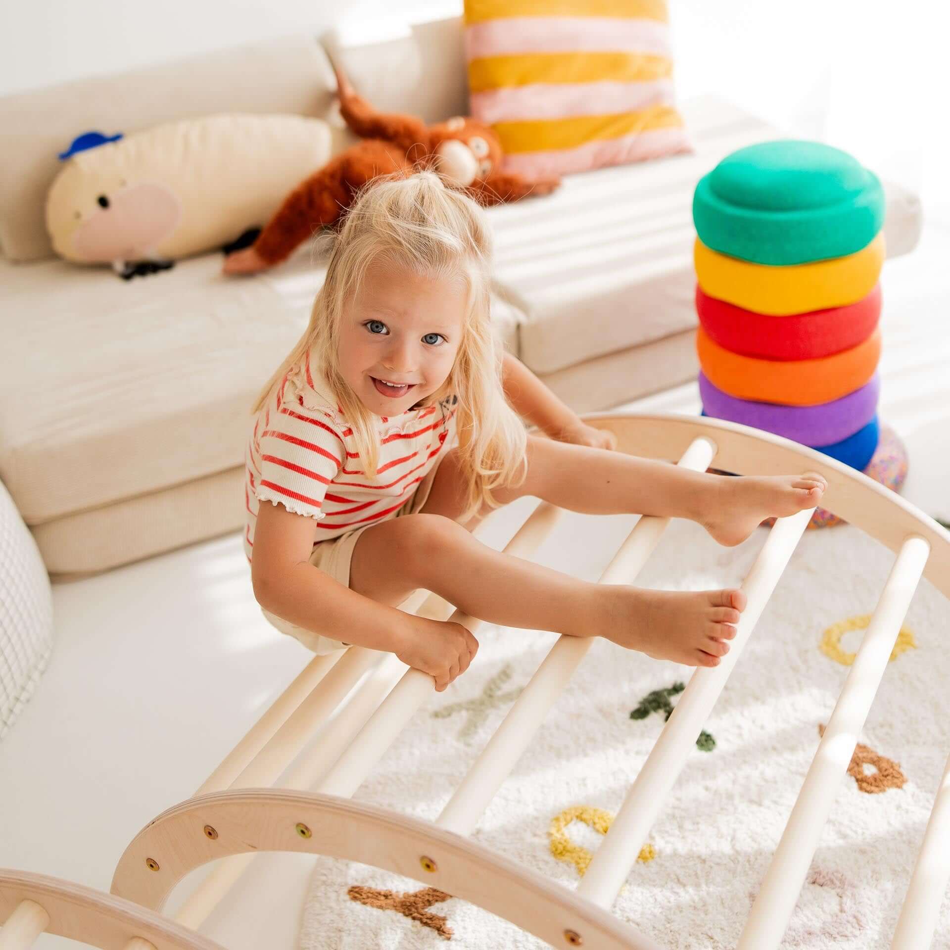 Fröhliches Kind, das auf einem Kletterbogen aus Holz spielt, ideal für Bewegungsförderung und Spielspaß.