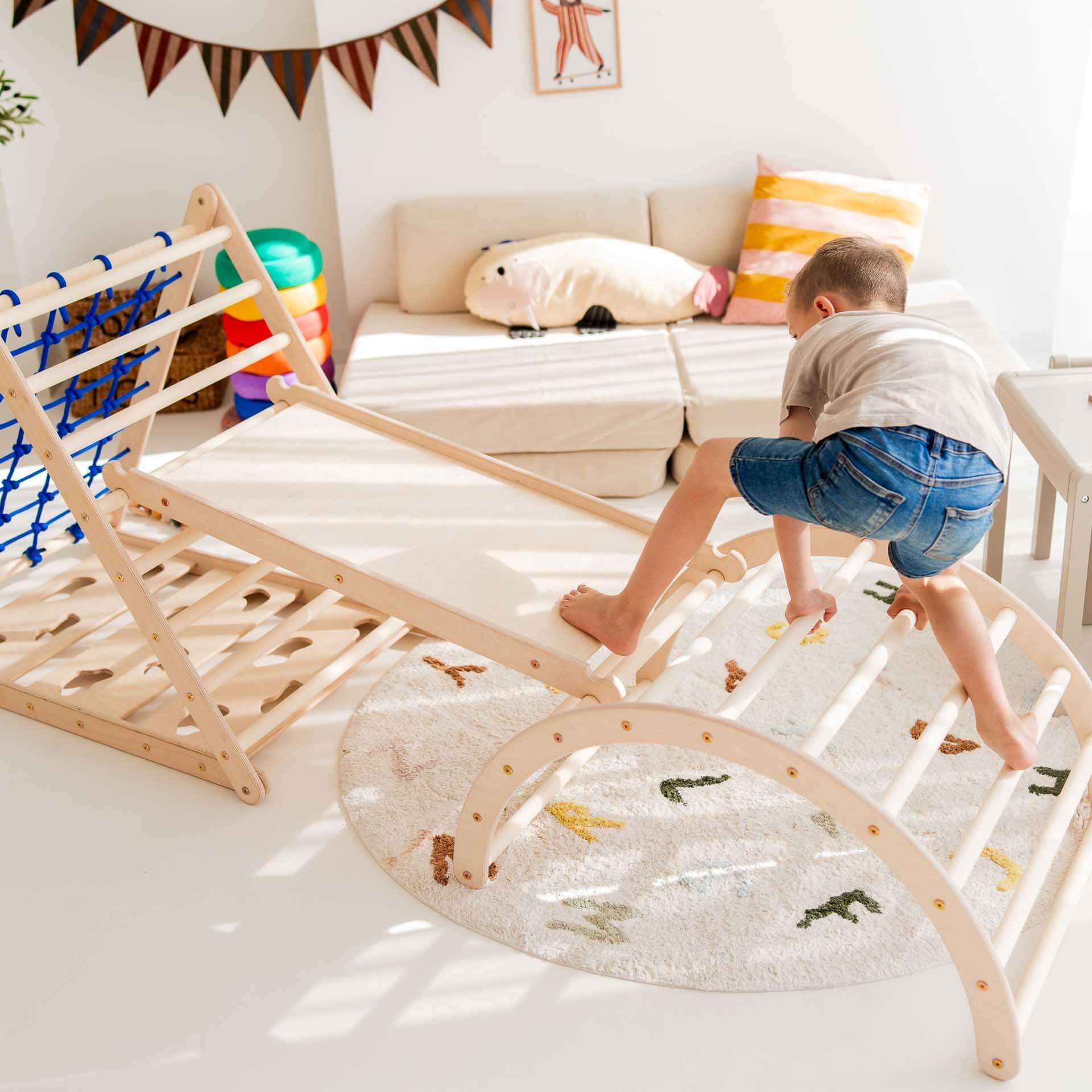 Kind klettert auf Kletterbogen Basic aus Holz in einem hellen Spielzimmer mit verschiedenen Größen.