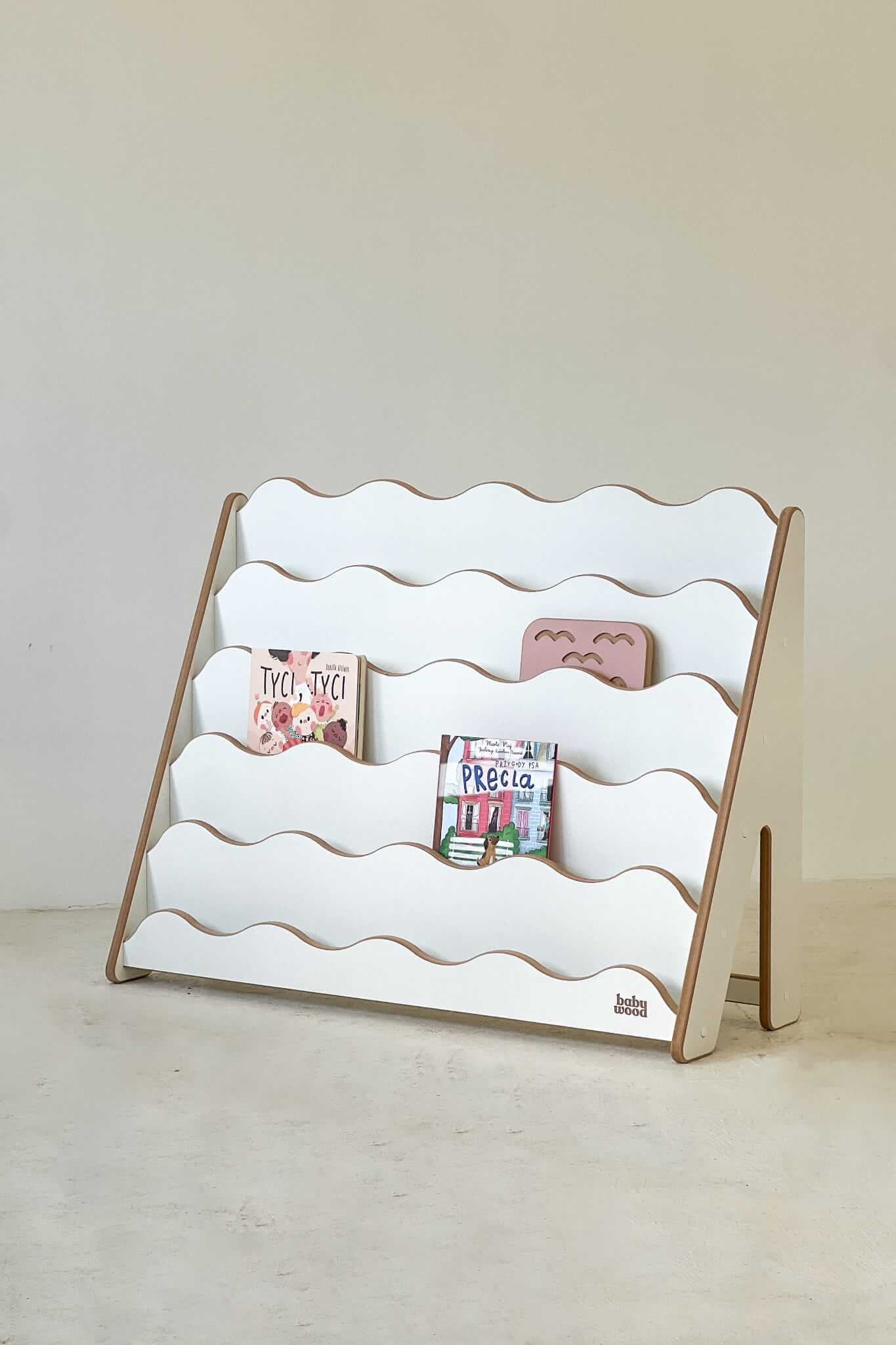 Bücherregal WAVE aus Holz für Kinder mit sanften Wellenlinien und bunten Büchern sichtbar. Perfekt für Geschichten!