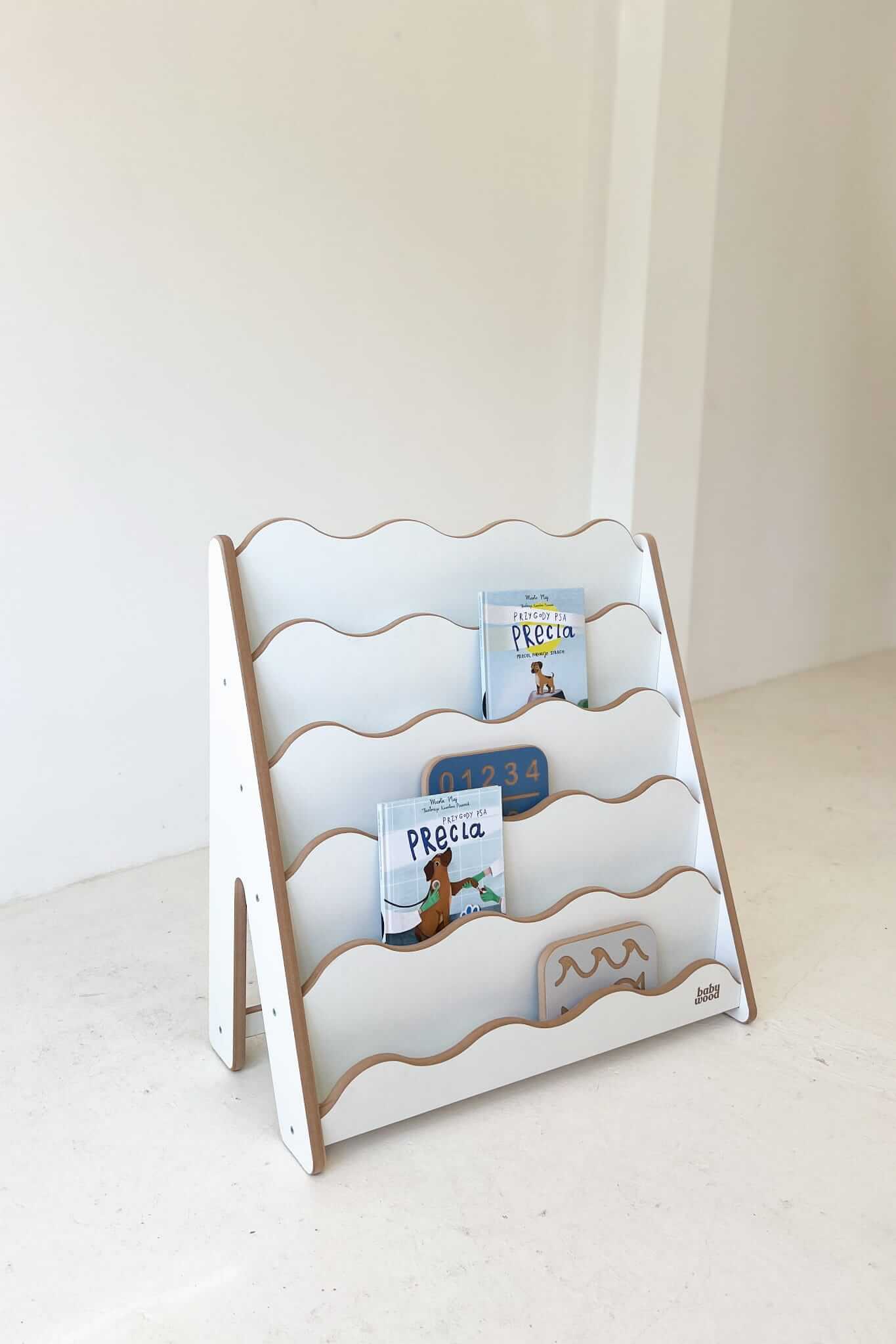 Bücherregal "WAVE" für Kinder, weißes Holzregal mit sanften Wellenlinien und sichtbaren Büchern.
