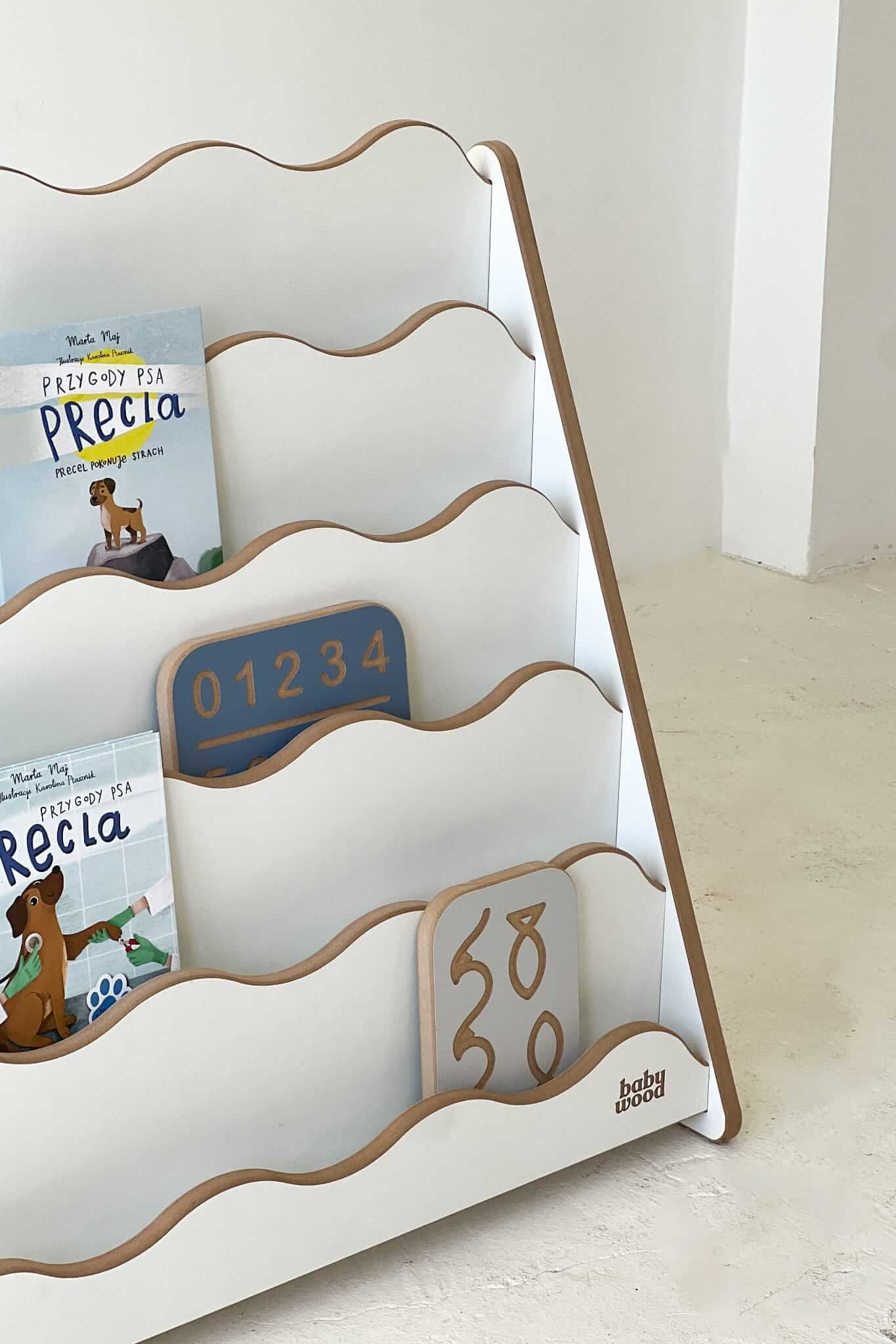 Bücherregal "WAVE" für Kinder aus Holz mit Sicht auf farbenfrohe Bücher und Schiebespielzeug.