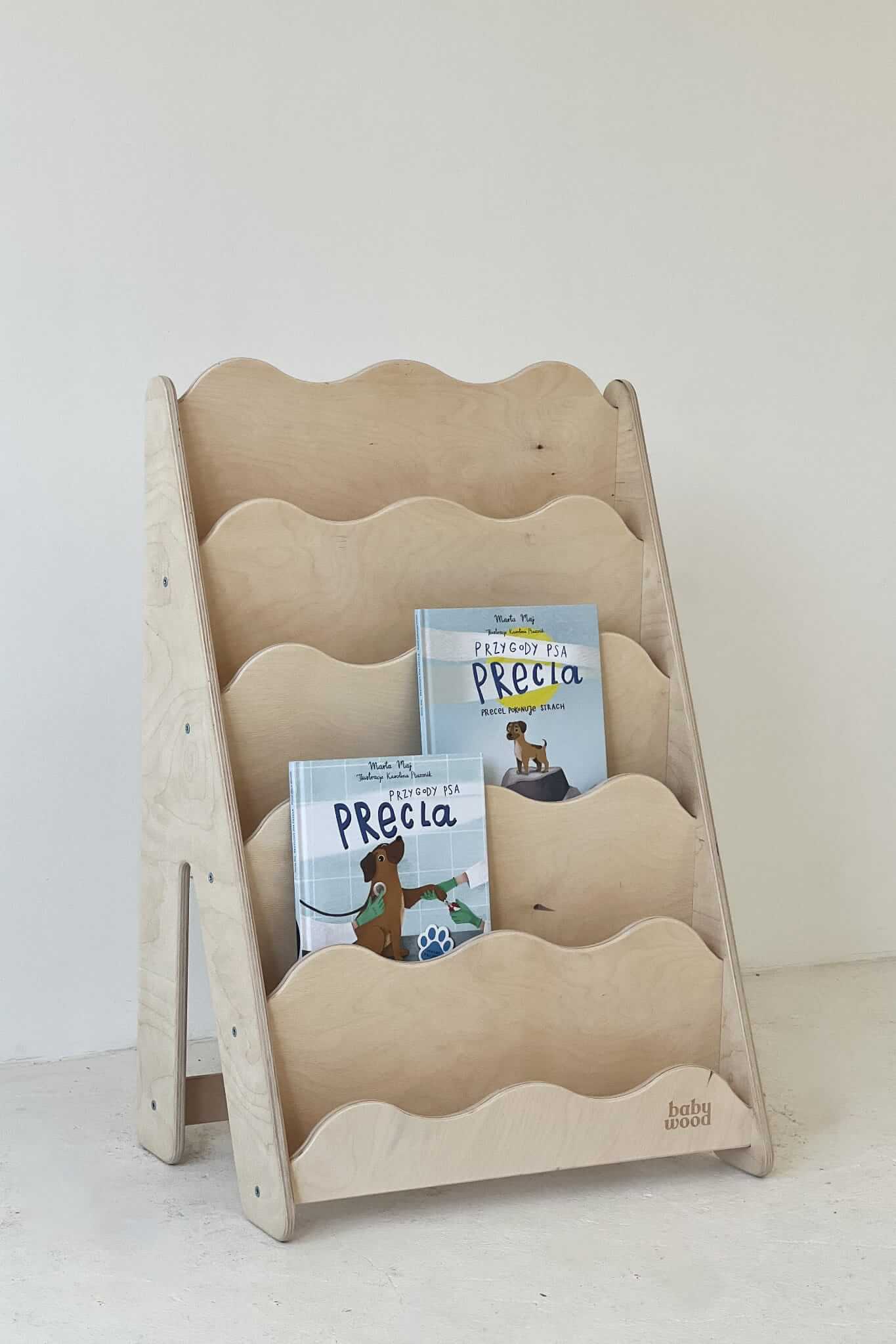 Bücherregal Wave aus Holz mit mehreren Fächern und Kinderbüchern für eine einladende Leseecke.