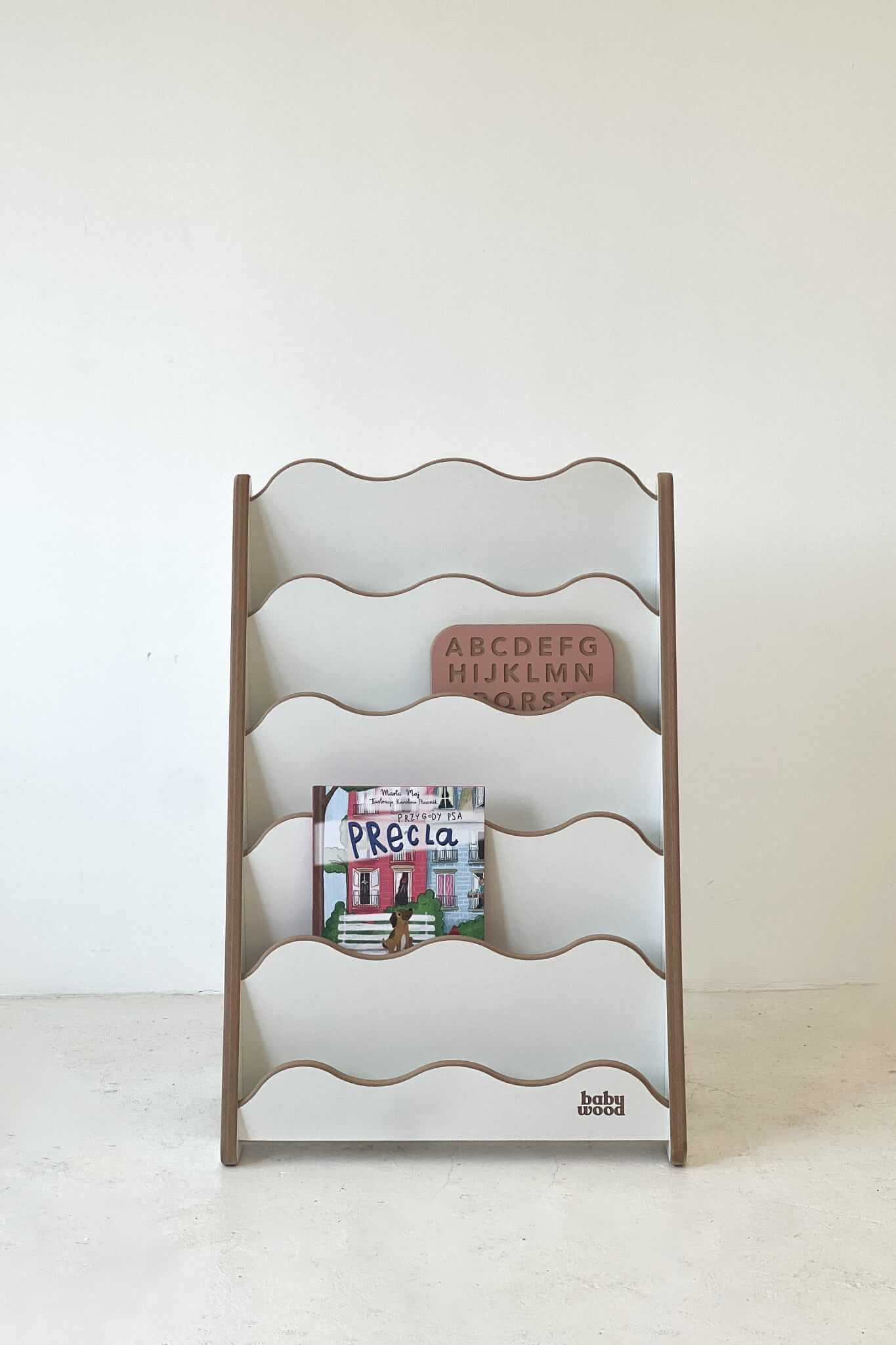 Bücherregal "WAVE" aus Holz für Kinder mit sanften Wellenlinien und bunten Buchcovern.