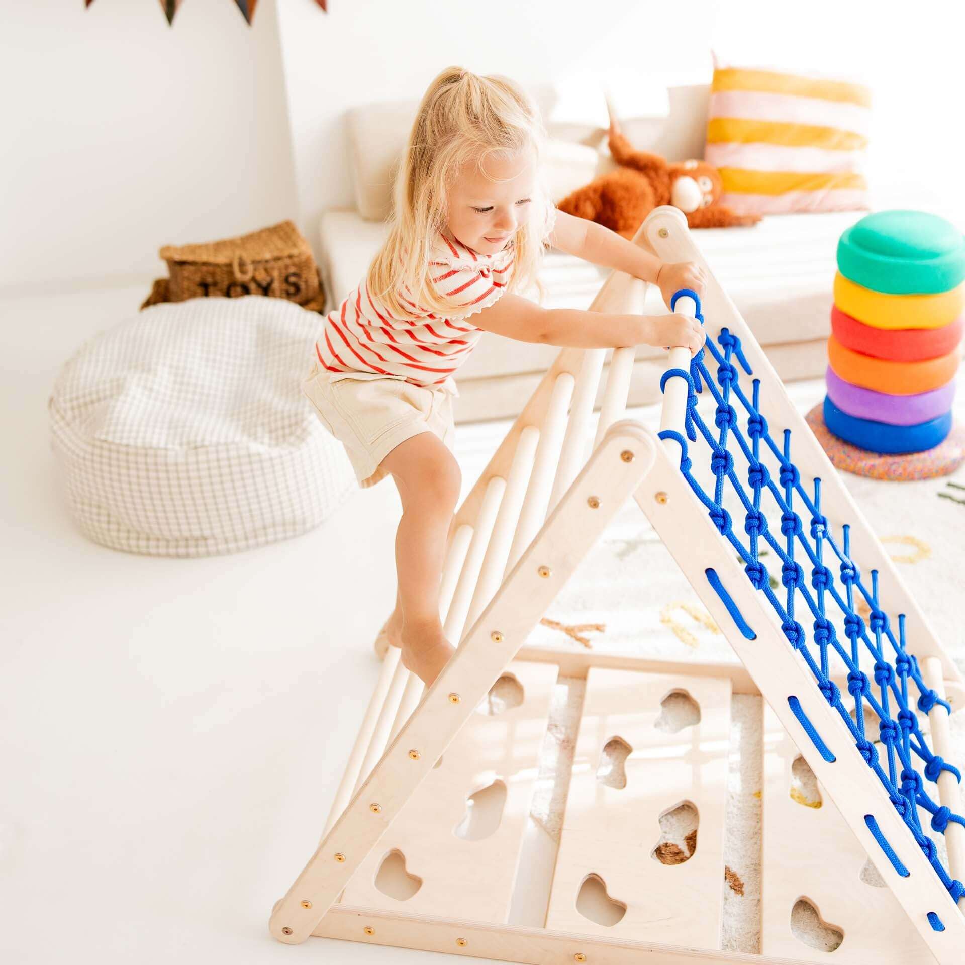 Kleine Künstlerin klettert auf dem Kletterdreieck Äffchen mit Sprossen und Netz für spielerische Bewegung.