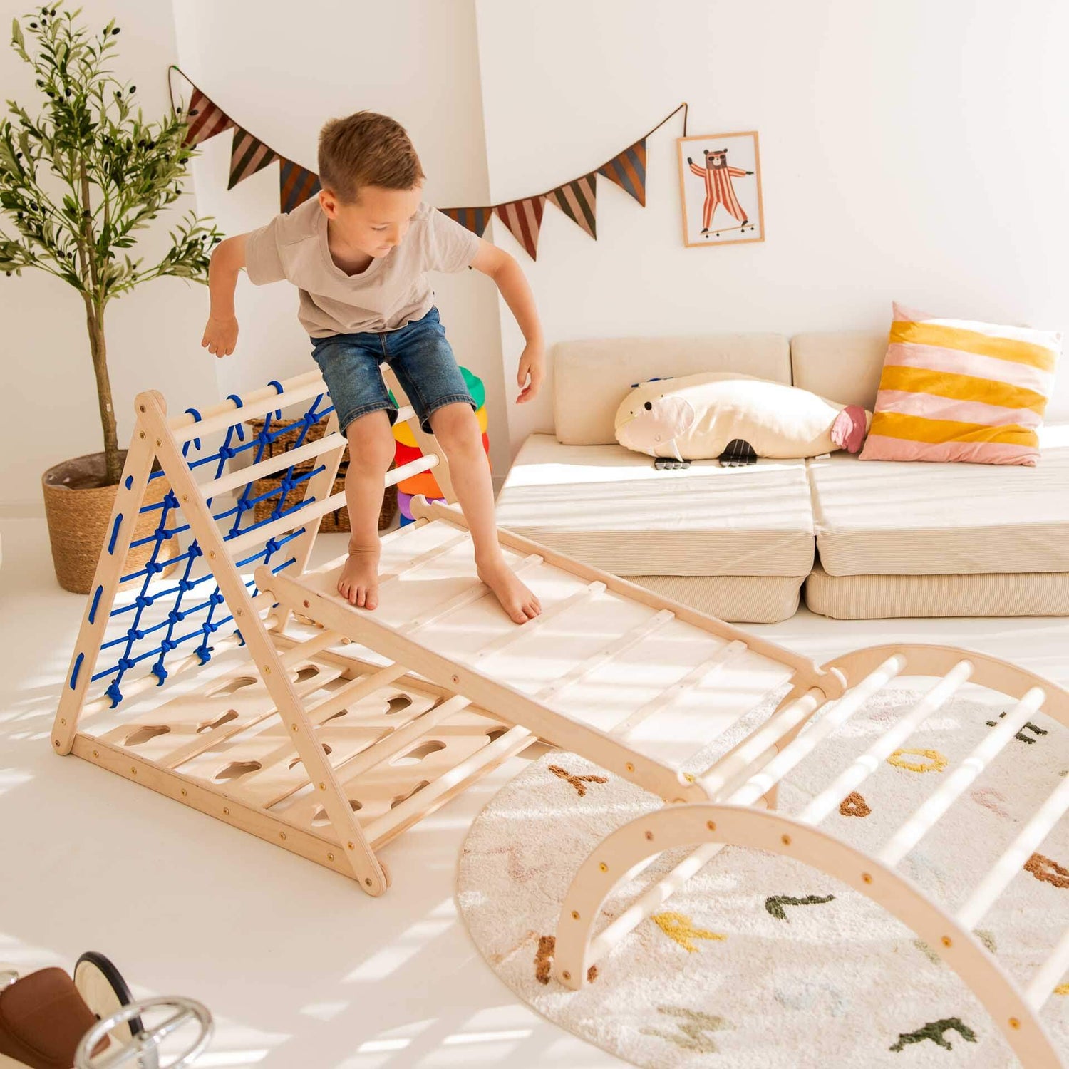 Ein Junge spielt auf dem Kletterdreieck Äffchen, das mit einem Kletternetz ausgestattet ist.