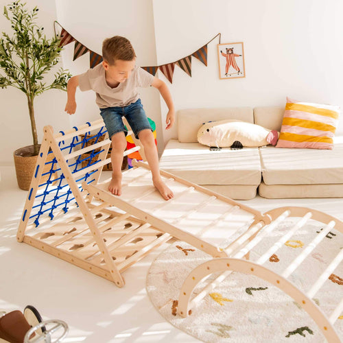 Ein Junge spielt auf dem Kletterdreieck Äffchen, das mit einem Kletternetz ausgestattet ist.