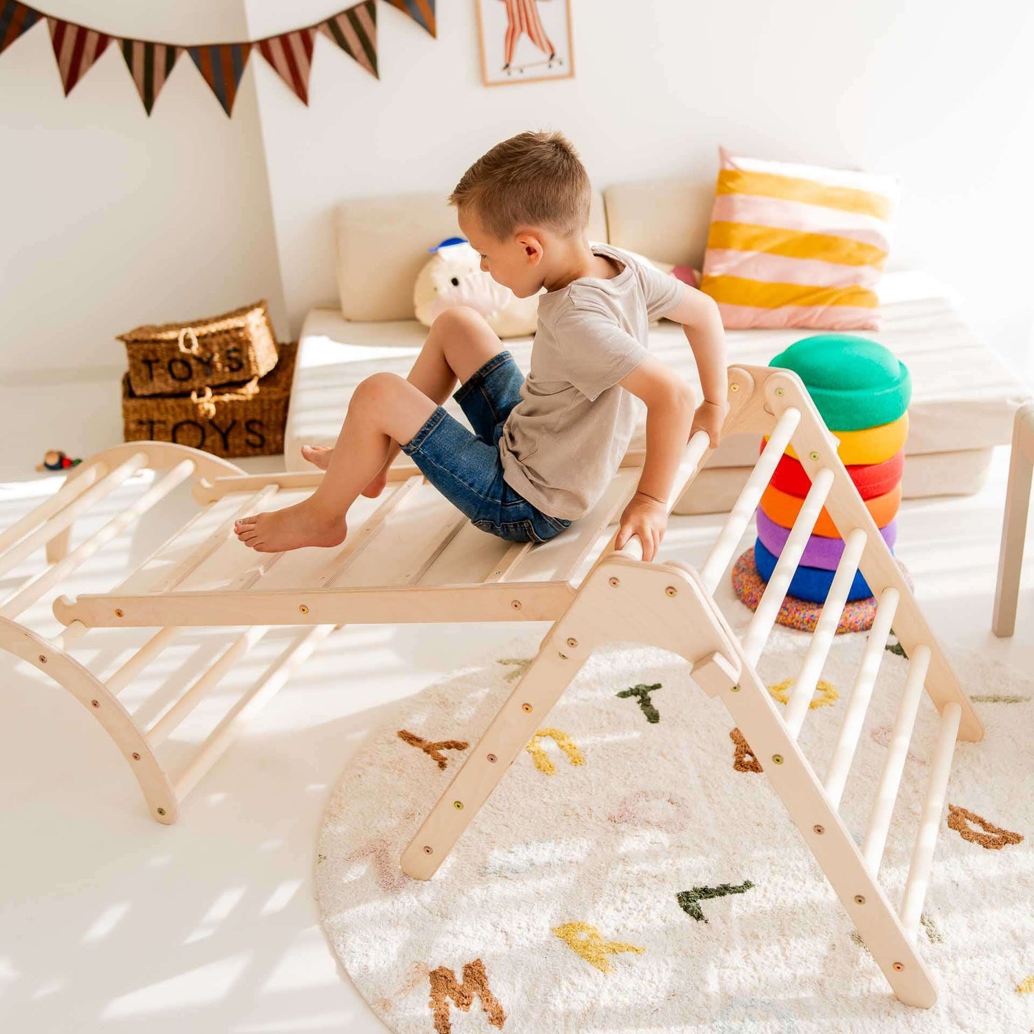 Ein Junge spielt auf dem Kletterset Panda mit Kletterbogen und Rutsche in einem hellen Spielzimmer.